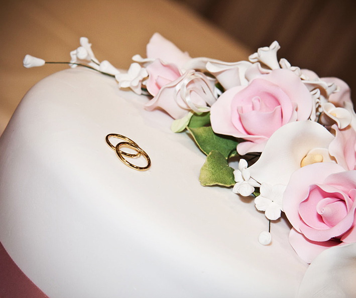 wedding cake decorated with rings and flowers