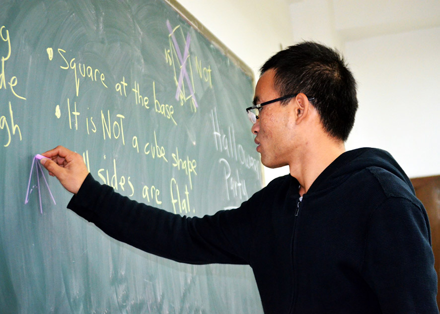 student writing math formula on black board